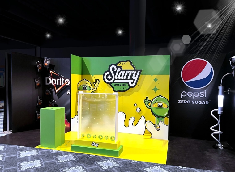 Display booth featuring Starry Lemon Lime with bright yellow and green colors, flanked by Doritos and Pepsi Zero Sugar branding. The Starry logo is prominent with cheerful cartoon imagery, enhanced by large format printing for an eye-catching appeal.