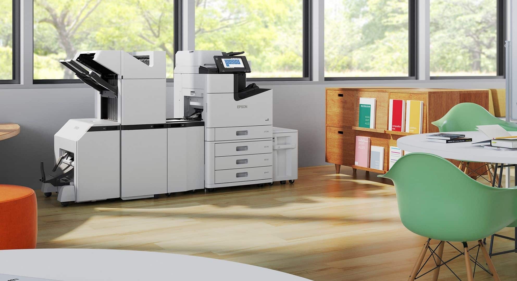 A white Epson printer and copier machine in an office with wooden floors, green chairs, a cabinet filled with books and folders, and efficient small format printing capabilities.