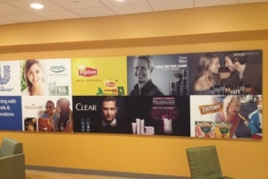 Wall display featuring various Unilever brand advertisements, including Lipton, Dove, Clear, and Fruttare, in a corporate office setting. The design also showcases innovative small format printing techniques for a crisp and engaging visual experience.