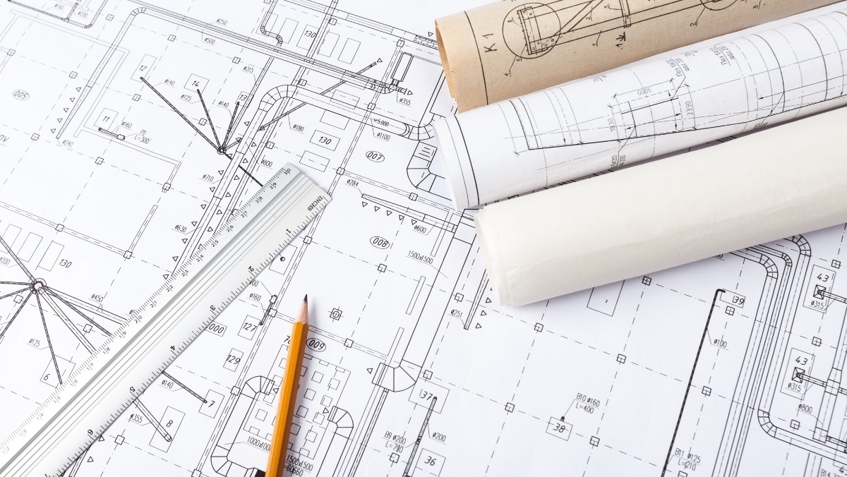 Architectural blueprints with a ruler and pencil on top, alongside rolled-up plans, highlight the meticulous process of design. Integrating 3D scanning adds precision to these blueprints, capturing every detail for seamless execution.