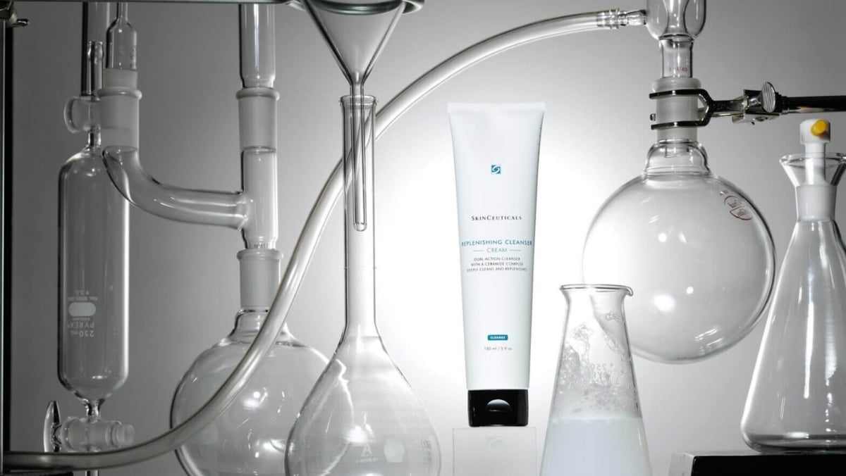 A tube of skincare product is surrounded by various glass laboratory equipment, including beakers, flasks, and funnels, highlighting a scientific and clinical environment akin to the precision found in small format printing.