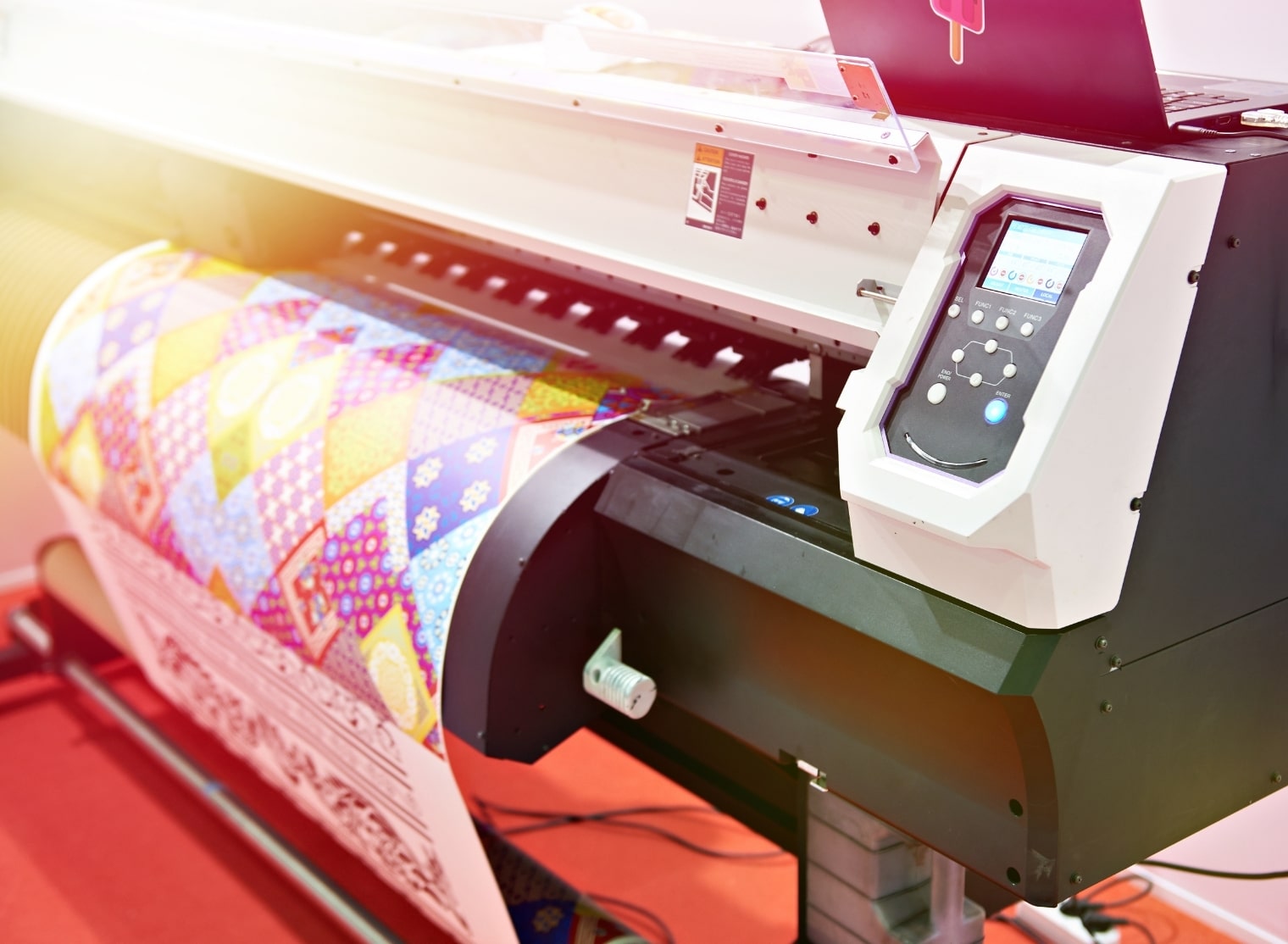 The large industrial printer specializes in large format printing, producing colorful patterned fabric with precision.