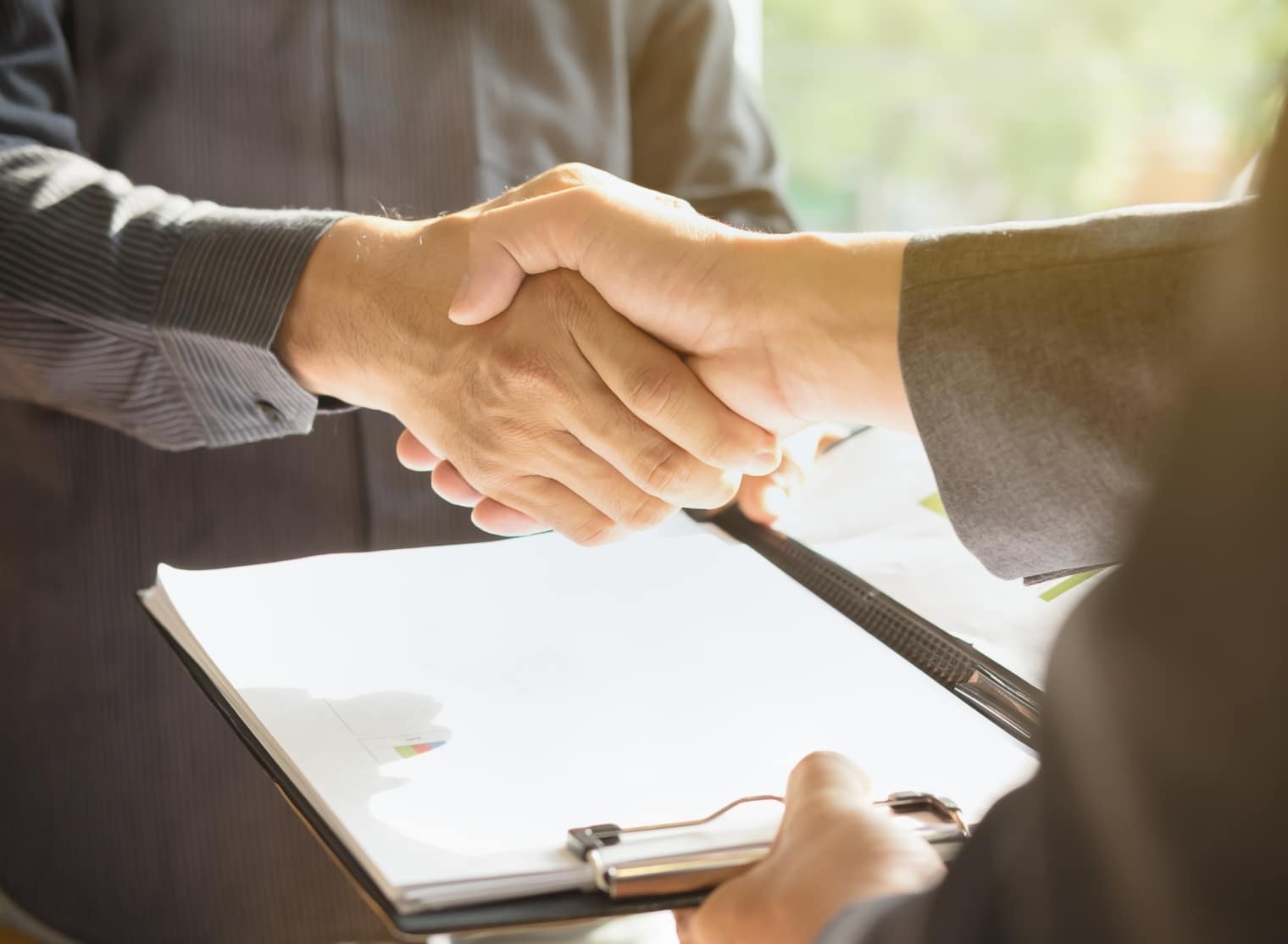 Two people are shaking hands over a clipboard with documents, indicating a possible agreement or partnership, perhaps in the realm of 3D printing.