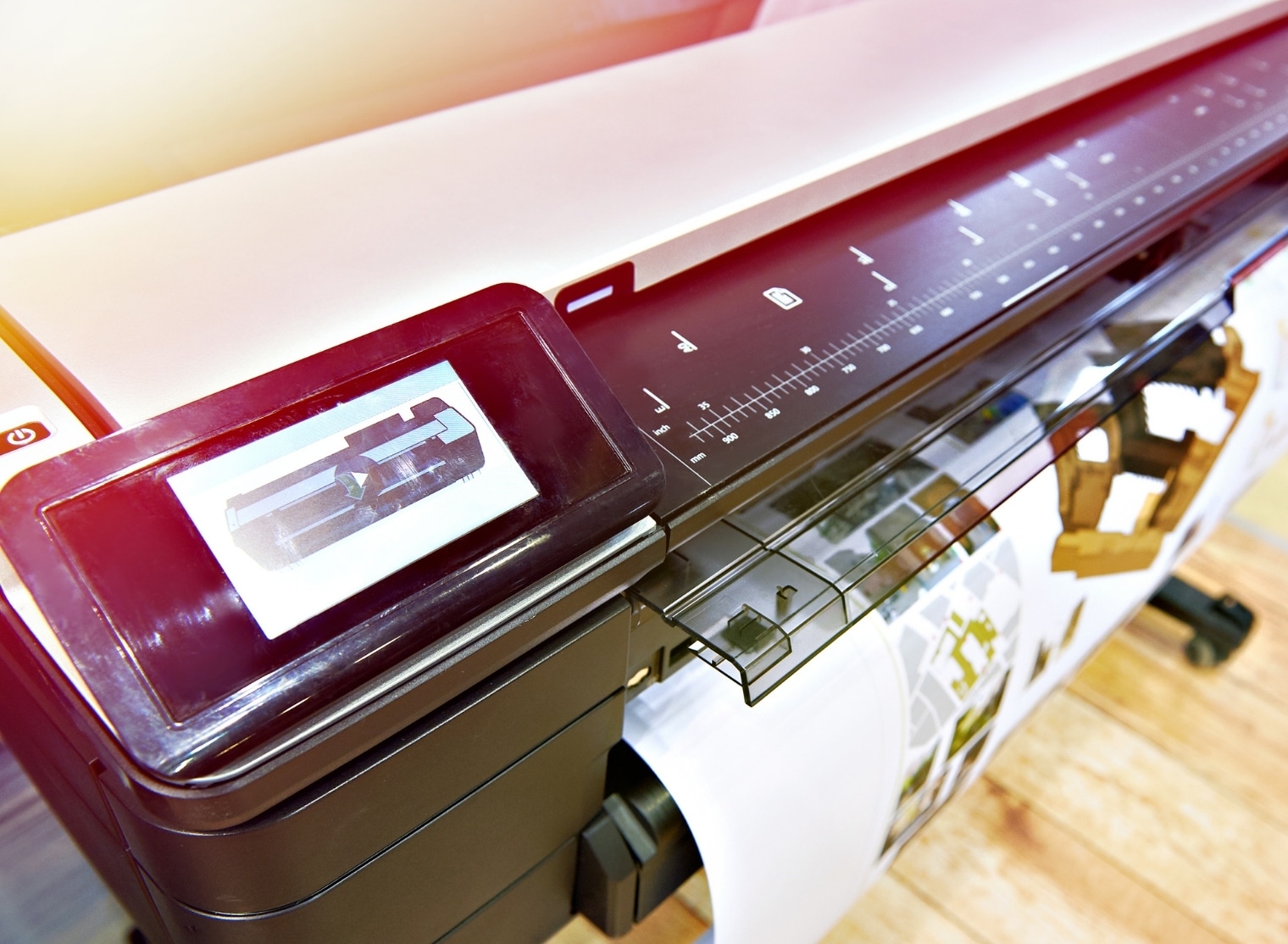 A state-of-the-art large format printer is seen meticulously printing a color document with detailed architectural designs. The control panel and measurement scale are clearly visible, showcasing precision in the large format printing process.