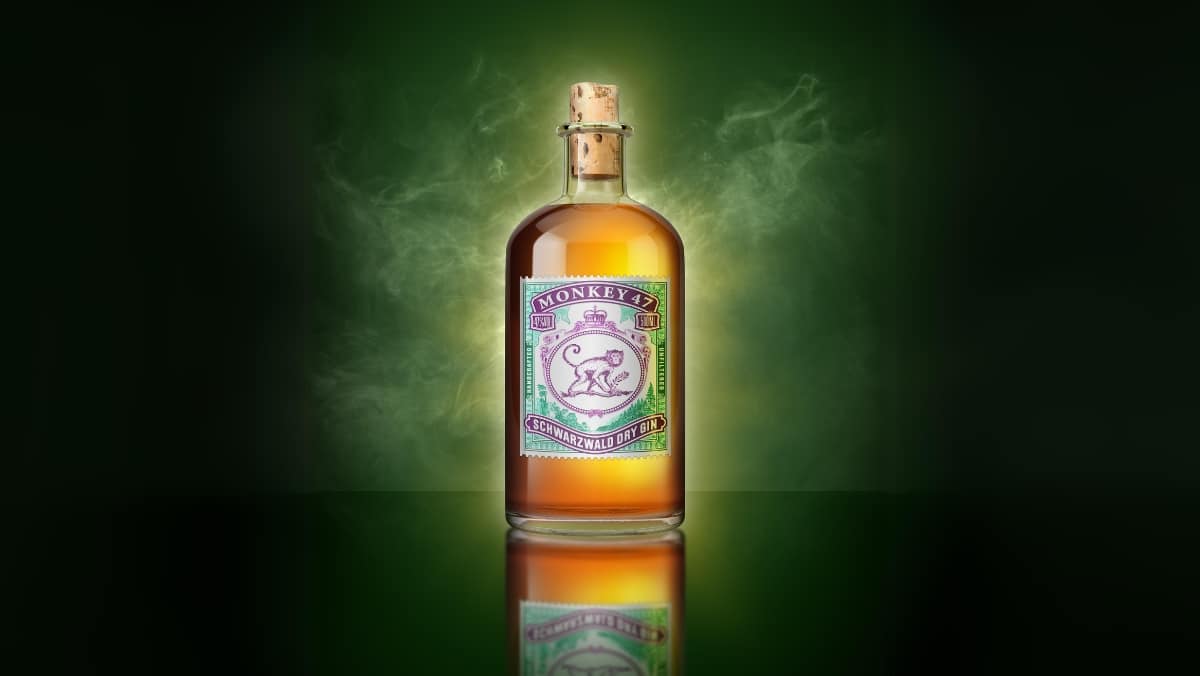 A bottle of Monkey 47 gin with a cork cap, set against a green smoky background, showcases the artistry akin to 3D printing services, where precision and creativity blend seamlessly.