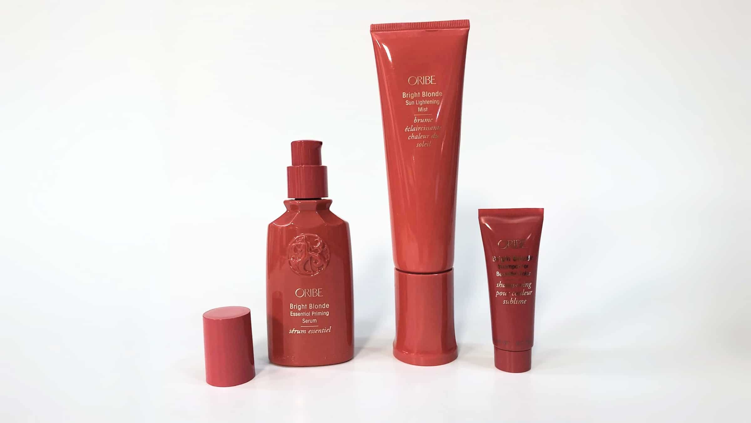 Image of four red Oribe Brilliance & Shine hair care products arranged in descending order of size against a white background, highlighting the precision almost akin to small format printing.