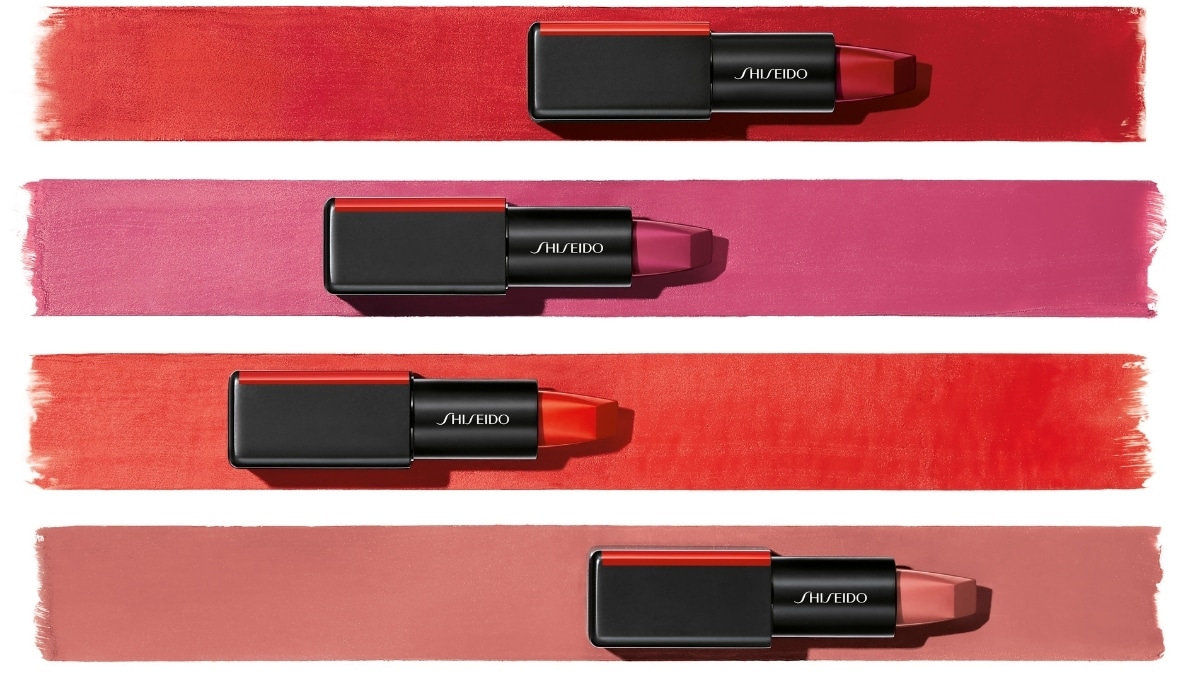 Four Shiseido lipsticks in various shades are artfully displayed on matching color swatches of red, pink, coral, and nude, showcasing precision akin to 3D printing services in their vibrant allure.